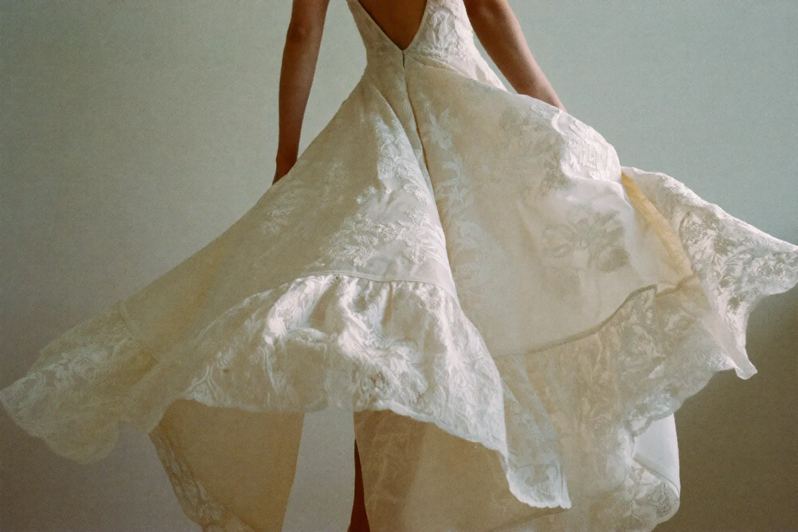 Boho Brautkleid aus fließender Spitze in weichem Tageslicht, Stoff im Mittelpunkt, ruhige editorial Aufnahme